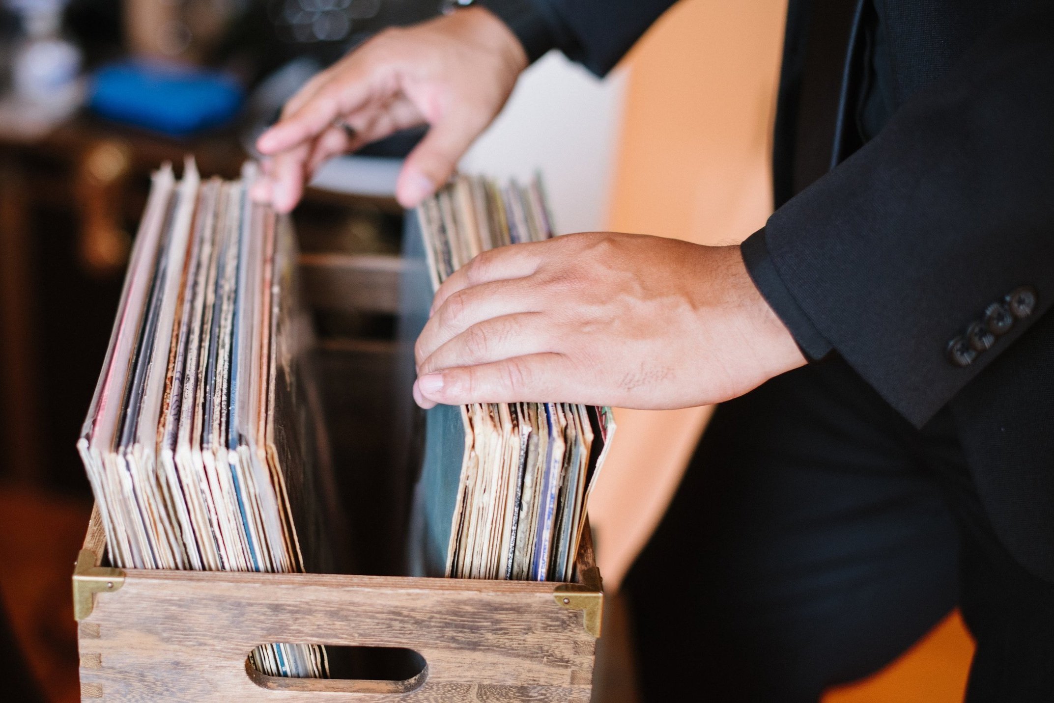 Hands selecting records from a vinyl crate
